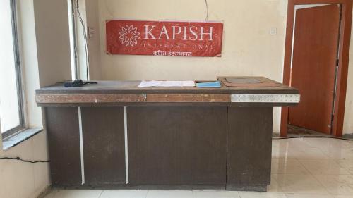 een houten bureau in een kamer met een bord aan de muur bij Hotel Kapish International Solapur 400 mts from Bus Stand and 500 mtr from railway station in Solapur