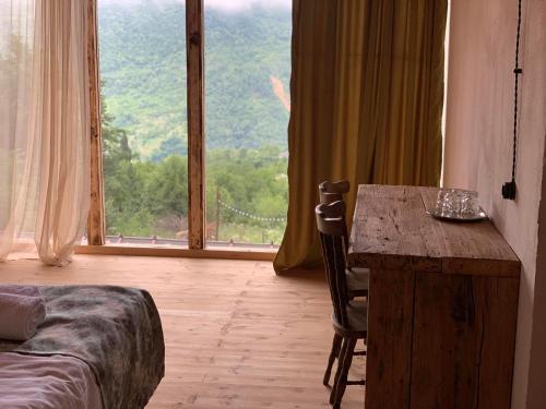 a room with a table and a large window at Korenishuli Veranda Wine Hotel in Tsʼageri