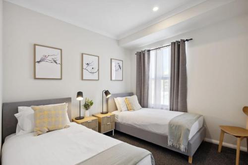 1 dormitorio con 2 camas y ventana en Jolly on James- 2BDR, en Perth