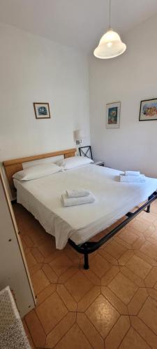 uma grande cama branca num quarto com um candeeiro em Bilocali con Giardino Via Sivori em Bonassola