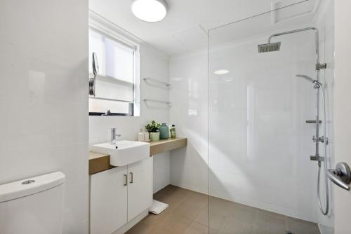 y baño blanco con lavabo y ducha. en Perth City Corporate 1BRD, en Perth