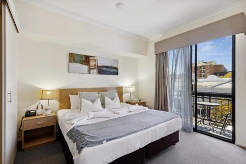 a bedroom with a large bed and a balcony at Perth City Corporate 1BRD in Perth