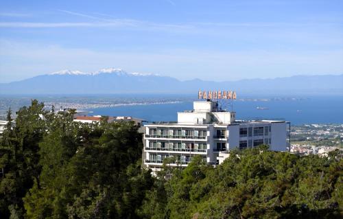 a building on top of a hill with water and mountains at Hotel Panorama in Thessaloniki