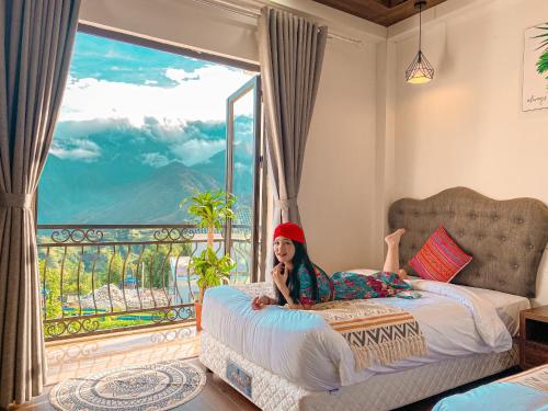 a girl laying on a bed in a room with a balcony at The Upper House Sapa in Sapa
