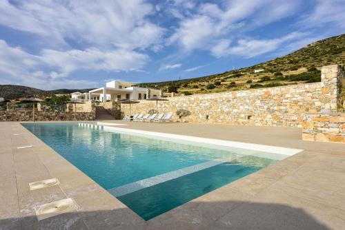 a swimming pool in front of a stone building at Stunning new villa with great pool area, magnificent panoramic sea view - Paros in Angairiá