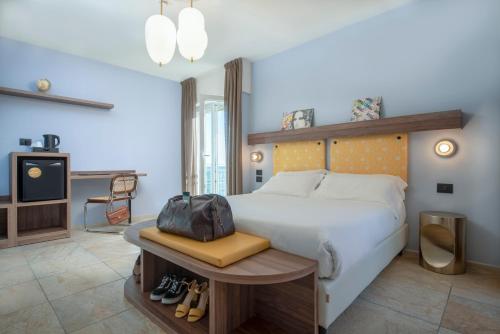 a bedroom with a large bed with a bag on a bench at Hotel Jolly Roger in Pietra Ligure