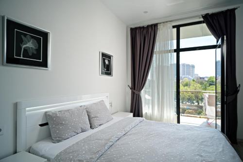 a white bedroom with a bed and a window at Апартаменты в Аркадии - Arcadia Sky Apartments in Odesa