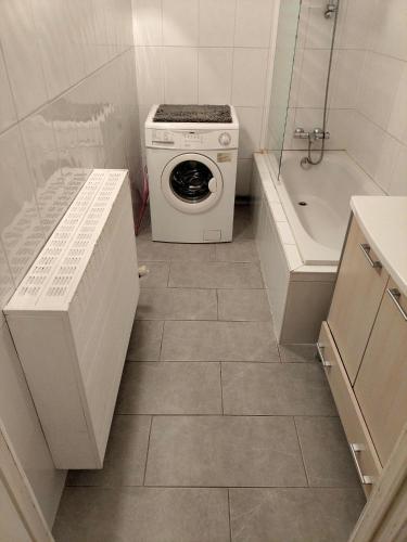 a small bathroom with a washing machine and a tub at Appartement voor gezin in Middelkerke