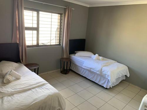 1 dormitorio con 2 camas y ventana en Proventures Self-catering House, en Ondangwa