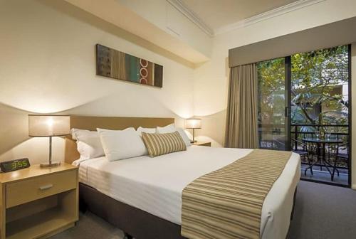 a bedroom with a large bed and a balcony at Narnia in Northbridge - One Bedroom in Perth