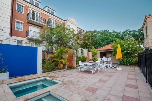 a patio with a table and chairs in front of a building at Narnia in Northbridge - One Bedroom in Perth