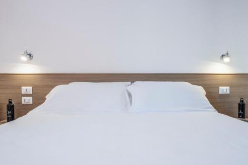 two beds in a hotel room with white sheets at Hotel Jolly Roger in Pietra Ligure
