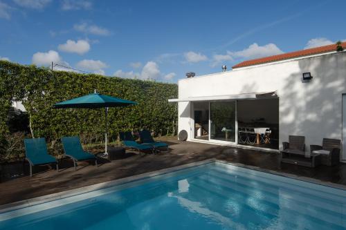 a swimming pool with chairs and an umbrella next to a building at Quinta do Ferreiro in Ponta Delgada