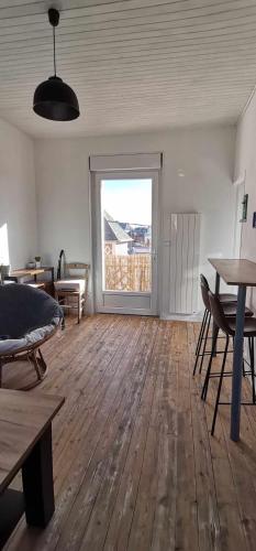 een woonkamer met een groot raam en een houten vloer bij Jolie Duplex à deux pas de la plage in Berck-sur-Mer