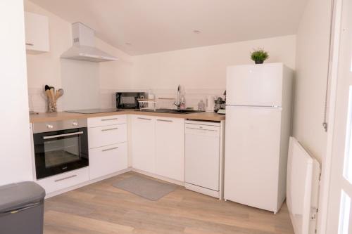 une cuisine avec des armoires blanches et un réfrigérateur blanc dans l'établissement La Vie En Gîte (Le Vintage), à Sainte-Florence