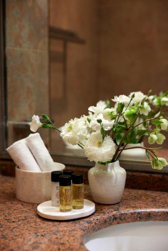 a bathroom counter with a vase of flowers on a sink at Hotel Panorama in Thessaloniki