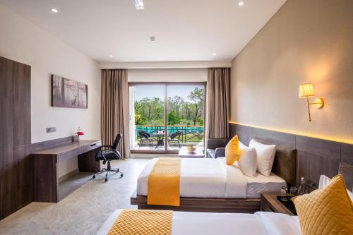 ラムナガルにあるShervani Pebbles And Pines Corbettのベッド2台とデスクが備わるホテルルームです。