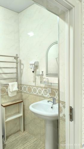 une salle de bain blanche avec un lavabo et un miroir dans l'établissement Bibikhanum Hotel, à Samarcande