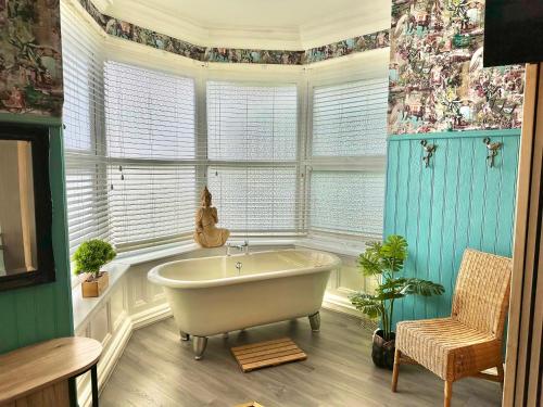 un bagno con vasca in una camera con finestre di Blue Buddha - Lemur Lodge - NEW MANAGEMENT 2024 - Bath in Bedroom with En-Suite - Short Stroll to the Beach! a Bournemouth