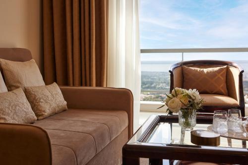 a living room with a couch and a table and a window at Hotel Panorama in Thessaloniki