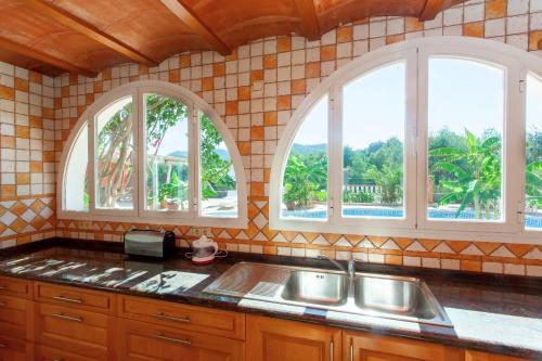 a kitchen with two windows and a sink at Can Ramos in Ses Fontanelles