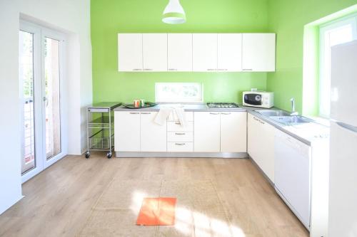 una cocina con armarios blancos y paredes verdes en Villa Bianca, en Cozzana
