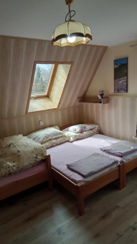 een slaapkamer met 2 bedden en een raam bij Pokoje gościnne Tessa in Zakopane