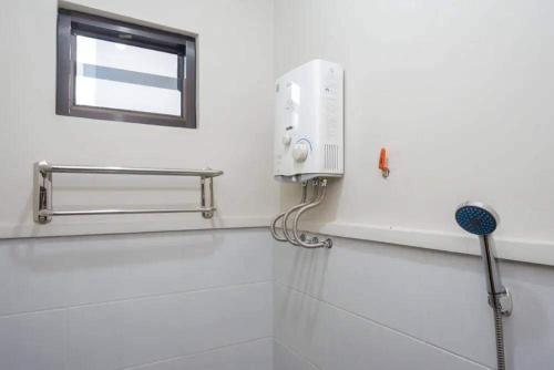 a white bathroom with a shower and a window at Ilfa Guest House syari'ah in Jatiwangi