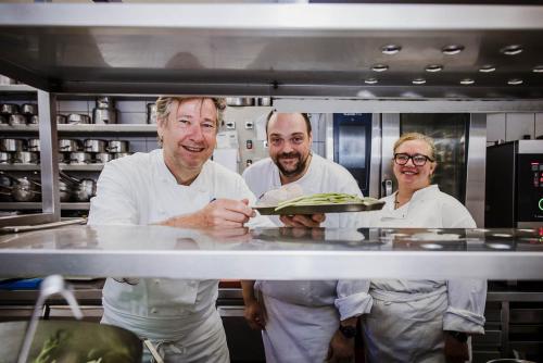 three chefs standing in a kitchen holding a plate at Hotel Geerts in Westerlo