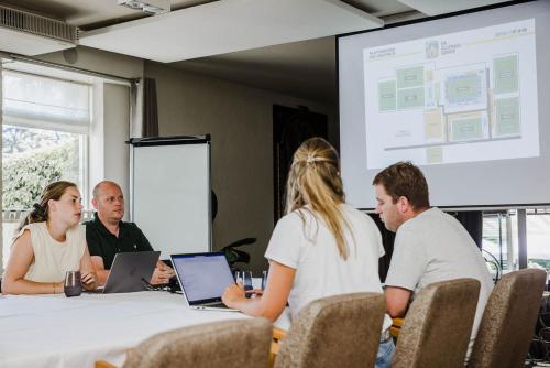 a group of people sitting around a table with laptops at Hotel Geerts in Westerlo