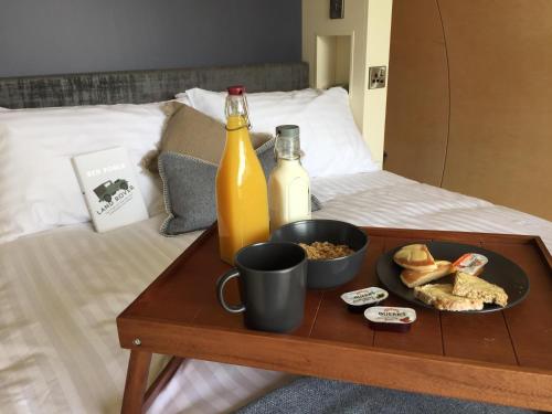 a tray with a bottle of wine and a plate of food on a bed at Thornfield Farm Luxury Glamping Pods, The Dark Hedges, Ballycastle in Stranocum