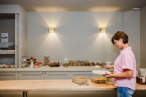 a woman standing in a kitchen preparing food at Hotel Geerts in Westerlo