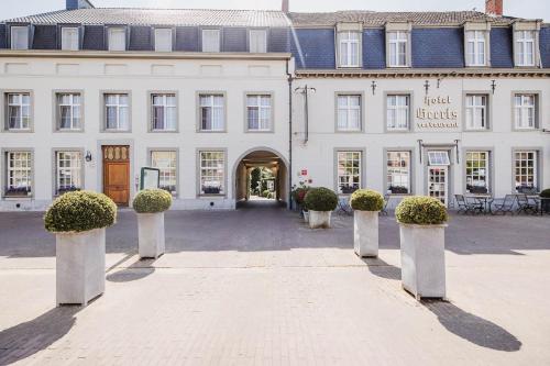 a large white building with potted plants in front of it at Hotel Geerts in Westerlo