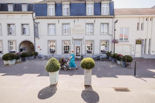 a woman walking in front of a building at Hotel Geerts in Westerlo