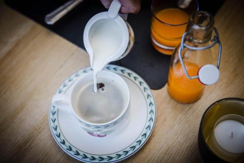 a person pouring milk into a cup of coffee at Hotel Geerts in Westerlo