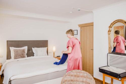 a woman in pink is cleaning a bed at Hotel Geerts in Westerlo