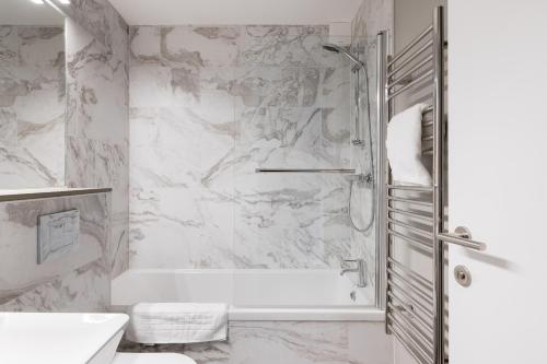 baño blanco con ducha y lavamanos en City Stay Apartments - Geldonia Court Bedford en Bedford