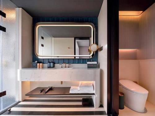 La salle de bains est pourvue d'un lavabo et d'un miroir. dans l'établissement Sofitel Shanghai North Bund, à Shanghai