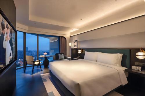 - une chambre avec un grand lit et une grande fenêtre dans l'établissement Sofitel Shanghai North Bund, à Shanghai