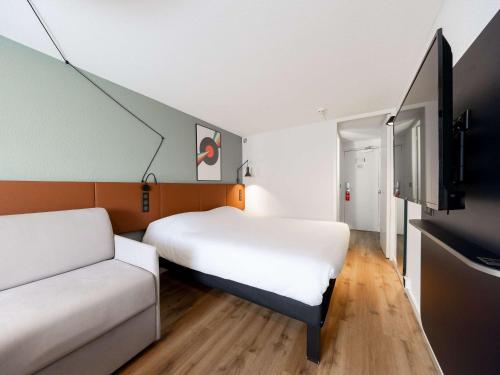 ボルドーにあるイビス ボルドー サントル メリアデックのベッド2台とソファが備わる小さな客室です。