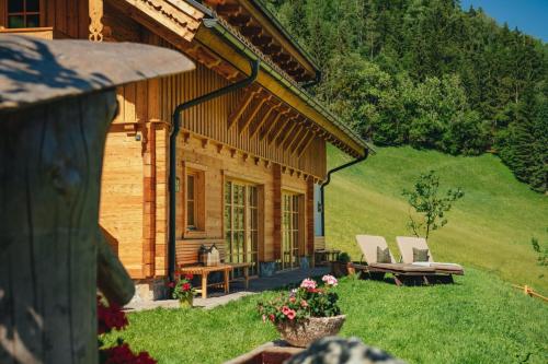 a log cabin with two chairs and a table at Almchalet Linharterhof in Haus im Ennstal