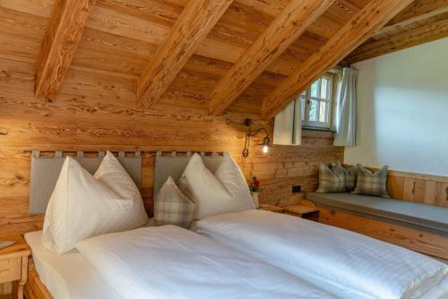 a bedroom with a white bed and a wooden ceiling at Almchalet Linharterhof in Haus im Ennstal