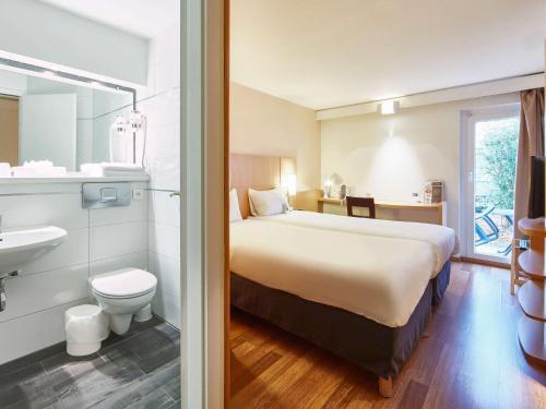 ein Hotelzimmer mit einem großen Bett und einem Bad in der Unterkunft ibis Haguenau Strasbourg Nord in Haguenau