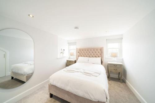 um quarto branco com uma cama e um espelho em The Crescent, Aberdeen City Centre Apartment em Aberdeen