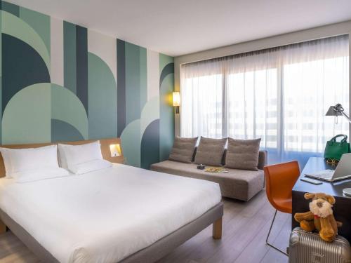 マドリードにあるノボテル カンポ デ ラス ナシオネスのベッドルーム1室(ベッド1台、ソファ、デスク付)