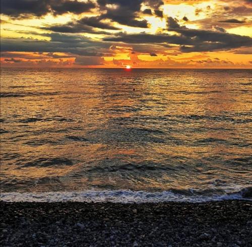 - un coucher de soleil sur la plage avec l'eau et les nuages dans l'établissement Vacation Home Nukri, à Gonio