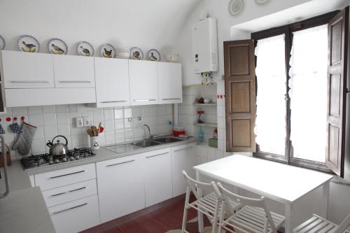 eine Küche mit weißen Schränken sowie einem Tisch und Stühlen in der Unterkunft Villa Coli in Calci