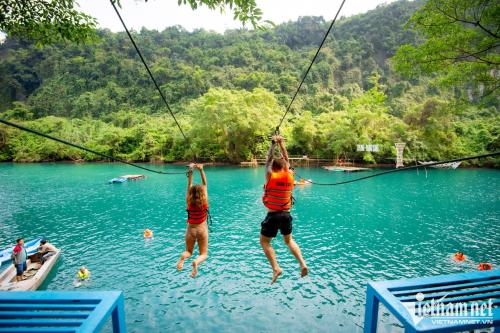 2 personnes sur un pont suspendu au-dessus d'un lac dans l'établissement Happy field homestay, à Phong Nha