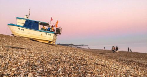 a boat sitting on top of a rocky beach at Lovely 1 Bedroom Ground floor apartment max 4 per in Hythe
