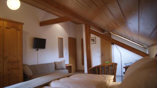 a bedroom with a bed and a couch and a tv at Gasthof zur Burgruine in Pottenstein